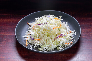 finely chopped white cabbage on plate over wooden background, concept raw food