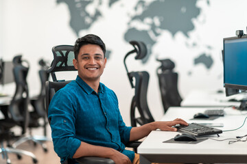 Casual business man working on desktop computer in modern open plan startup office interior. Selective focus 