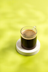 Glass of coffee, cup with espresso in sunny morning on podium and green background. Aroma, ristretto. Mug of coffee.