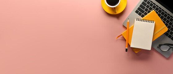 A top view of office utilities flat lays such as note books, laptop and a cup of coffee on an empty pink space on a background, for business and technology concept.