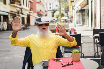 Senior hipster man using virtual reality headset outdoor at bar restaurant - Metaverse concept -...