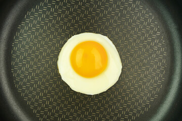 Fried egg in a pan. Food on a black background. Top view       