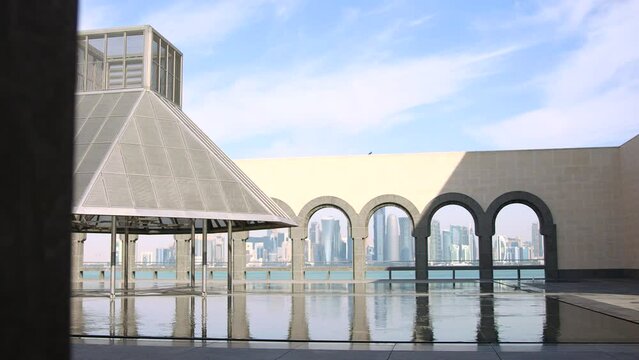 Exterior museum of islamic art doha qatar with skyline in background.