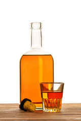 Glass and bottle of alcohol with a cork on a white background.