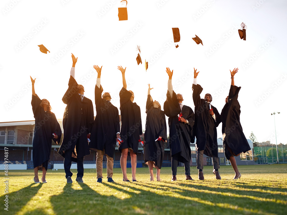 Poster Theyve reached the end of their academic years. Shot of a group of university students throwing their hats in the air on graduation day.