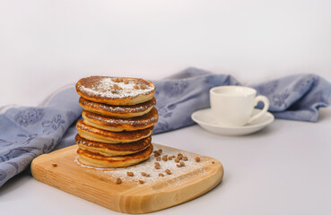 A stack of pancakes with berries and powdered sugar on a wooden board. on a white background.