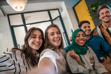 Group of business people during break from the work taking selfie picture while enjoying free time in relaxation area at modern open plan startup office. Selective focus 