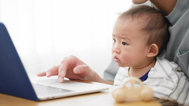 ノートパソコンを赤ちゃんに見せる父親
