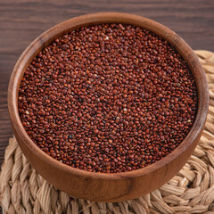 Organic red quinoa in a bowl on wooden table background.