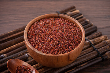 Organic red quinoa in a bowl on wooden table background.
