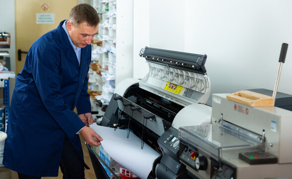 Repairman changes paper roll in plotter. High quality photo