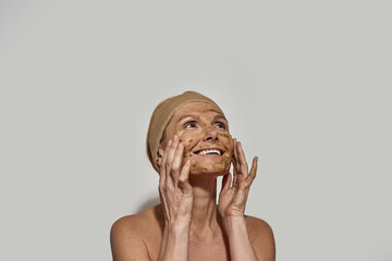 Woman with coffee and salt scrub on face look up