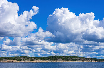 Skerries and coastline under a bright cloudy blue sky in the Koster fjord between the Koster...