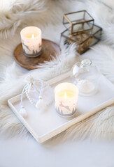 Cozy home decor with faux fur blanket, burning candles and interior decorations