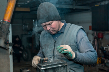 Fototapeta na wymiar Welder solders copper car radiator with gas torch