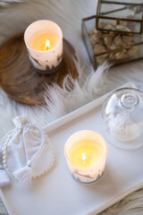Cozy home decor with faux fur blanket, burning candles and interior decorations