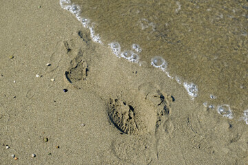 waves and sand on the beach close-up, footprints across the horizon. Seaside background. Copy space. Summer background