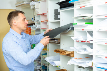 Office worker puts paper and printing film on the shelves. High quality photo