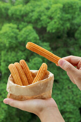 Hand Picking a Stick of Fresh Fried Churro from Paper Bag