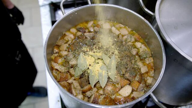 zupy, wsypywanie majeranku do zupy, wrzucanie liści laurowych do zupy / pouring herbs into boiling soup, cooking soup, pouring marjoram into soup 