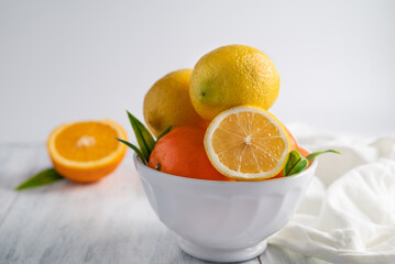 On a light background, a blurred image of lemons and tangerines in a white plate.