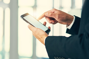 Engaging with clients in mobile form. Cropped shot of corporate businessmen texting on a cellphone.