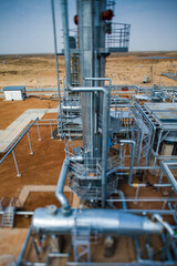 Grey metal pipes of distillation tower (column). Oil refinery plant in the yellow desert. Tilt-shifted partially blurred photo. Kazakhstan, Kyzylorda region. CNPC company