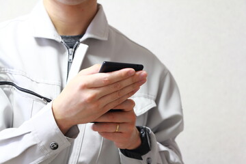 作業着でスマートフォンを使う人