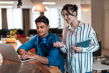 Multiethnic business people man with a female colleague working together on tablet and laptop computer in relaxation area of modern startup office