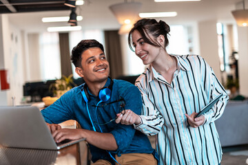 Multiethnic business people man with a female colleague working together on tablet and laptop computer in relaxation area of modern startup office