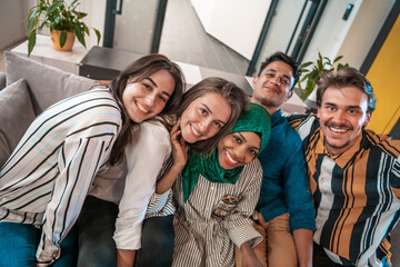 Group of business people during break from the work taking selfie picture while enjoying free time in relaxation area at modern open plan startup office. Selective focus 