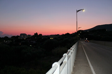 Landscape with sky turned red at sundown and the road to the village.