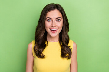 Portrait of attractive amazed sincere cheerful wavy-haired girl wow reaction isolated over bright green color background