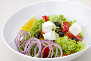 Greek salad with lettuce, olives, tomato, feta cheese, onion and lemon, wholesome and healthy food, diet and weight loss, proper nutrition