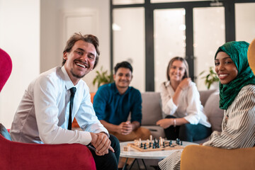 Multiethnic group of business people playing chess while having a break in relaxation area at modern startup office.