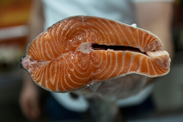A slice of fresh carcass of red fish in the hand of the seller in the store. Close-up. Healthy food and diet.