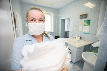 Fototapeta na wymiar A nurse in the hospital is straightening the bed linen. Hospital attendants.