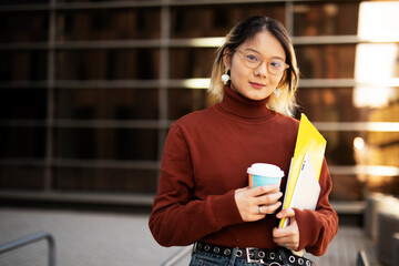 Beautiful Chinese woman enjoy in fresh coffee. Young fashion woman holding coffee cup while walking aroung the city