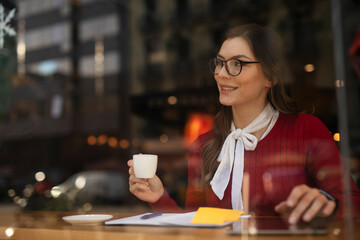 Beautiful young woman using digital tablet in cafe. Happy smiling woman enjoy in fresh coffee.