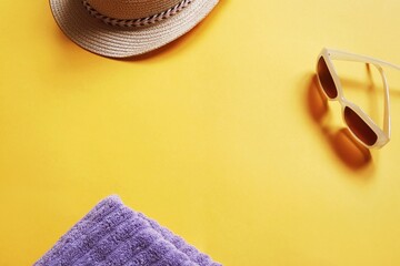 Flat lay composition photo summer beach essentials on a bright yellow background. Sun hat, purple towel and sunglasses. Mockup photography for design, free space for text