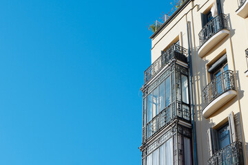 Fototapeta na wymiar Old-fashioned corner of classical building with elegant balconies in the centre district of Madrid, Spain. Vintage Spanish architecture