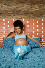 Portrait of a relaxed and happy black pregnant woman resting on her bed.