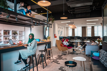 Fototapeta na wymiar Group of casual multiethnic business people taking break from the work doing different things while enjoying free time in relaxation area at modern open plan startup office