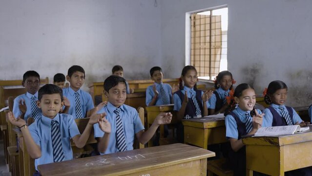 Young school kids in uniform applauding or clapping at classroom - concept of growth, entertainment, inspiration and childhood lifestyle