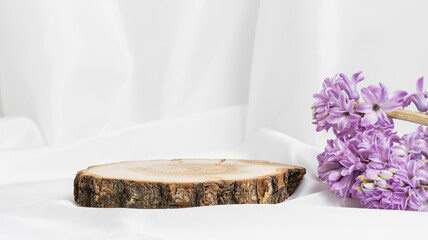 Round empty wooden podium with spring hyacinth flowers on white textile, display to product,...