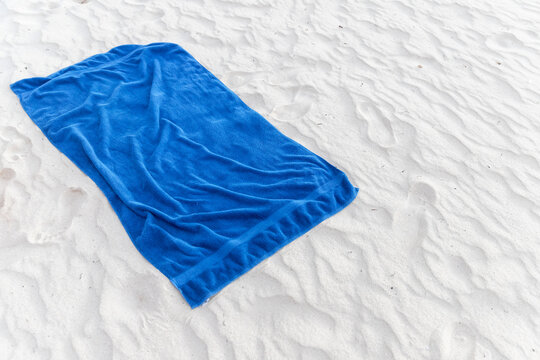 Blue cotton towel lays on sandy beach