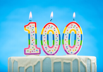 Blue Birthday Cake with 100 candles on Top on a Blue Background