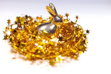gold bunny in the tinsel nest on the white background