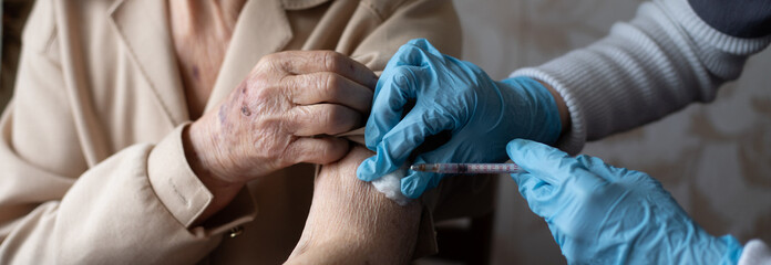 Nurse making vaccine injection to elderly patient - obrazy, fototapety, plakaty