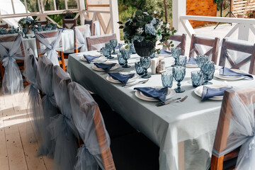 Blue glasses, plates and utensils on a festive table with flowers.